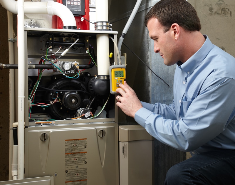 An HVAC technician completing furnace repairs and maintenance