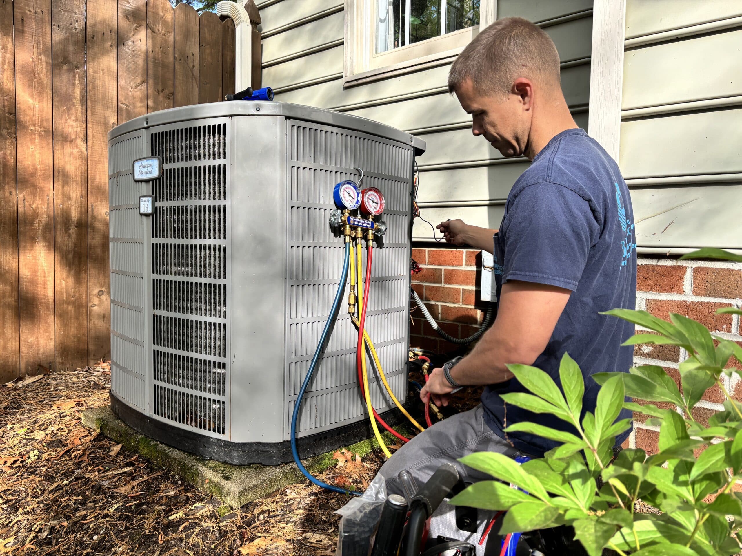 Jason checking refirgerant lines on an outdoor straight AC unit.