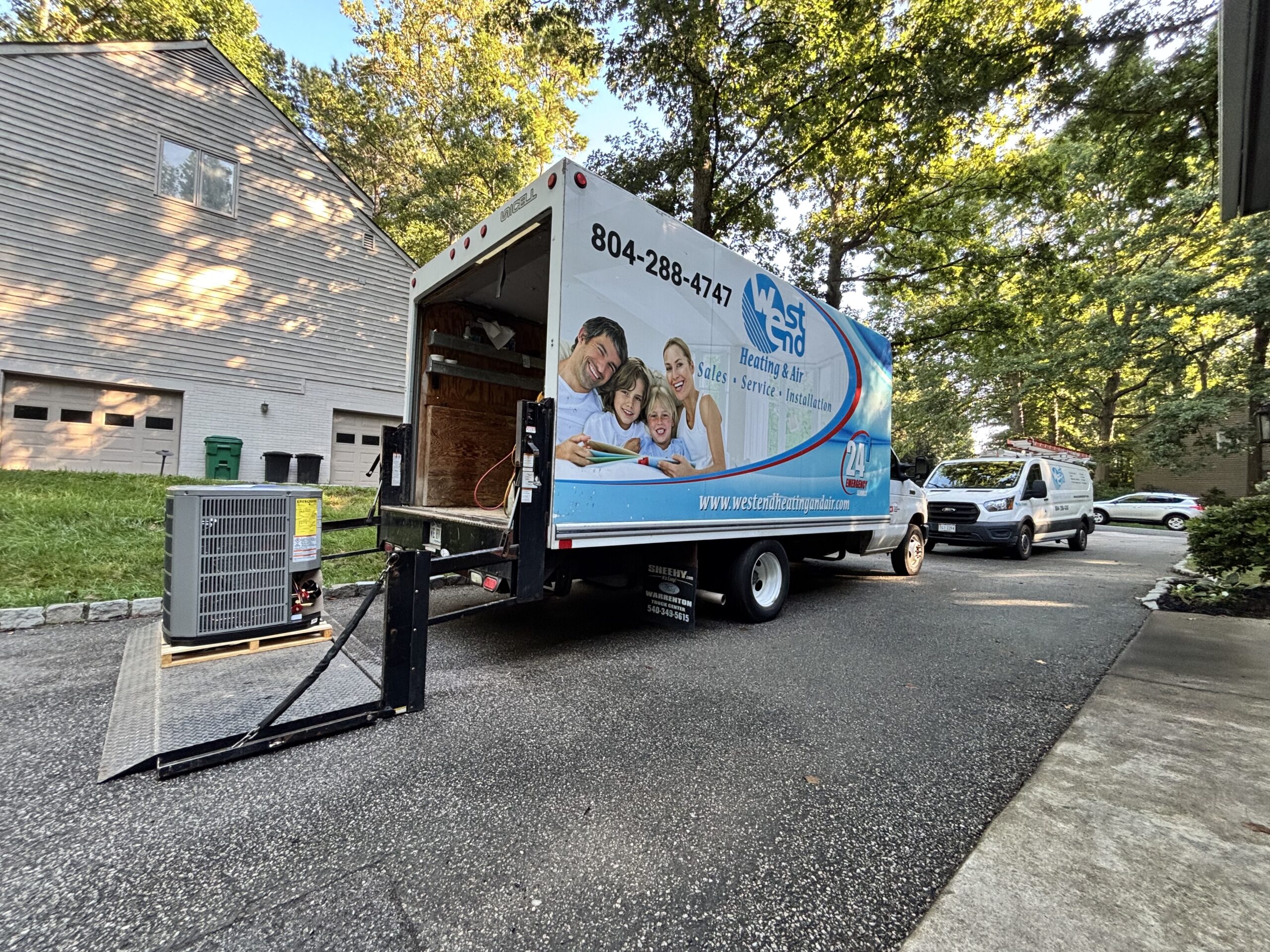Large Box Truck sitting in residential driveway with an air conditioner being installed